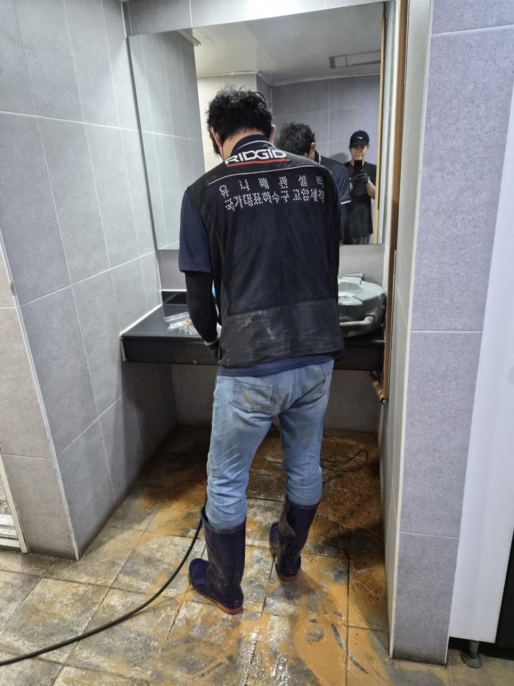 화장실에서 고압세척 장비로 작업하는 모습