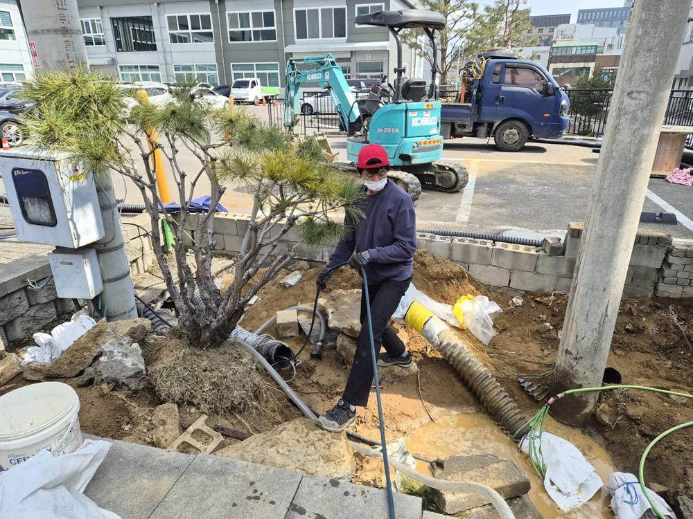 건물 외부 배관 옆에서 장비로 작업하는 모습